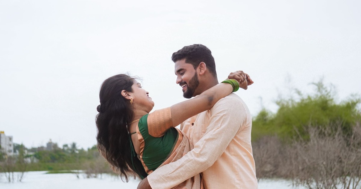 Indian couple joyfully embracing near a water body, exuding happiness and connection.
