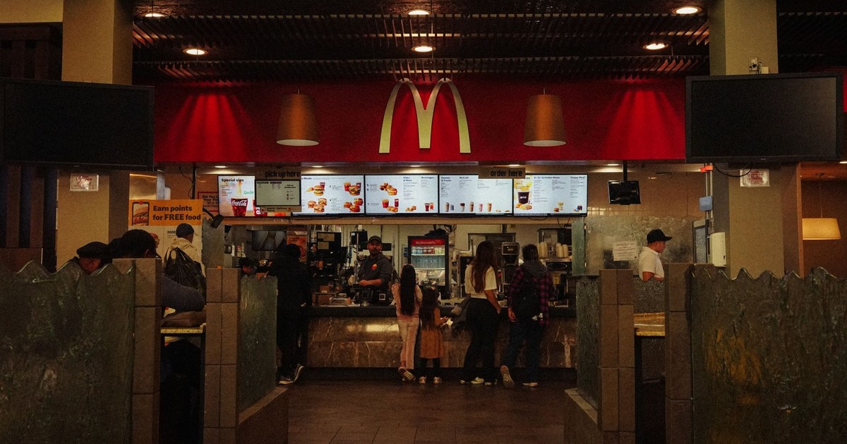 A bustling scene at a McDonald's restaurant counter with customers and staff in an indoor setting.