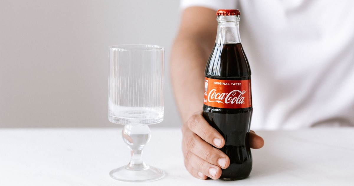 Crop unrecognizable young guy in white t shirt demonstrating bottle of cold coke