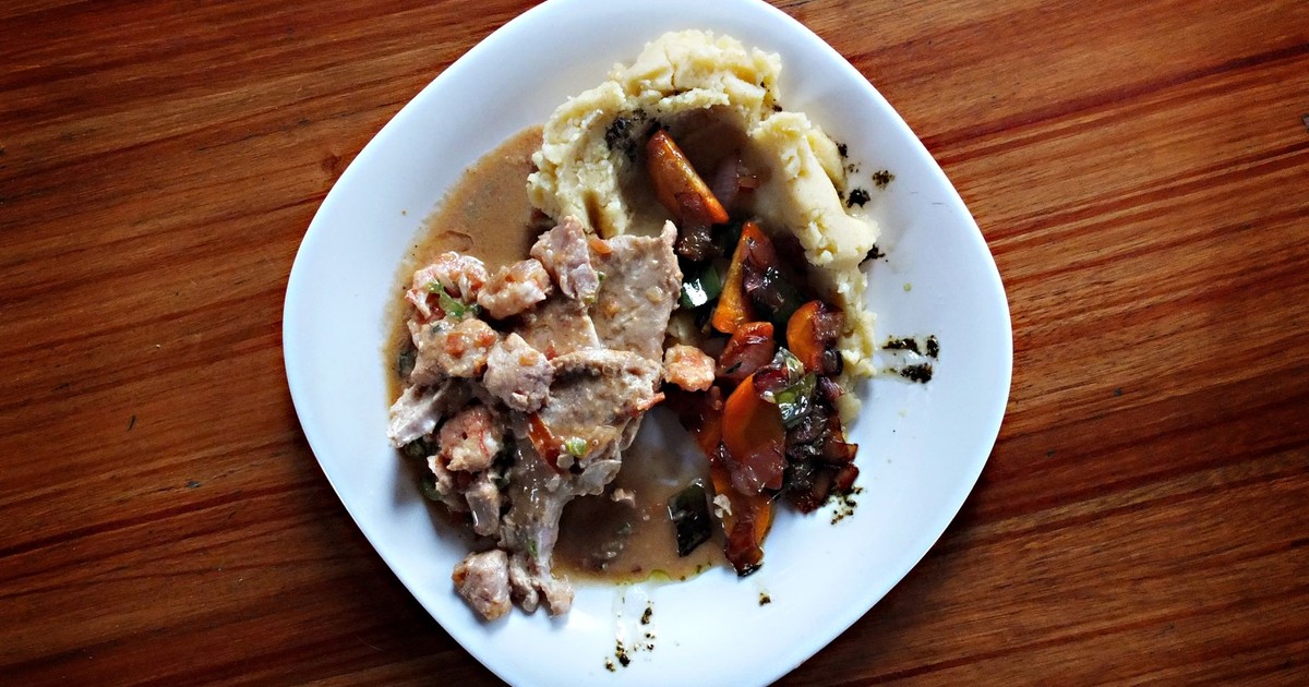 A savory dish of meat and vegetables with mashed potatoes on a wooden table.