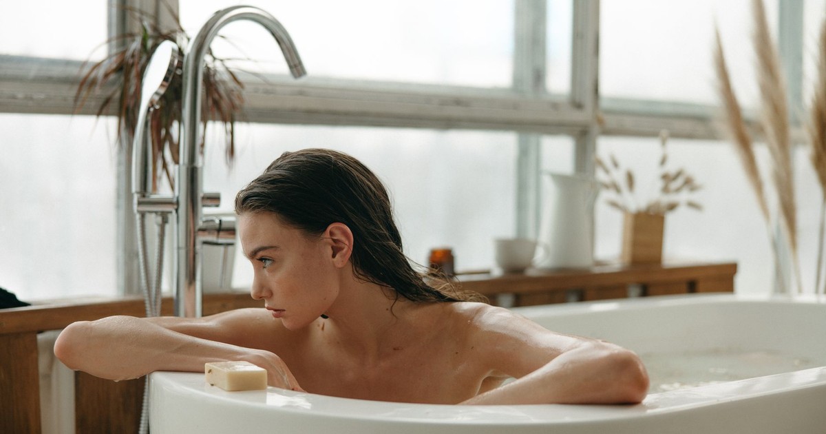A woman indulging in a peaceful bath experience with natural light and relaxation.