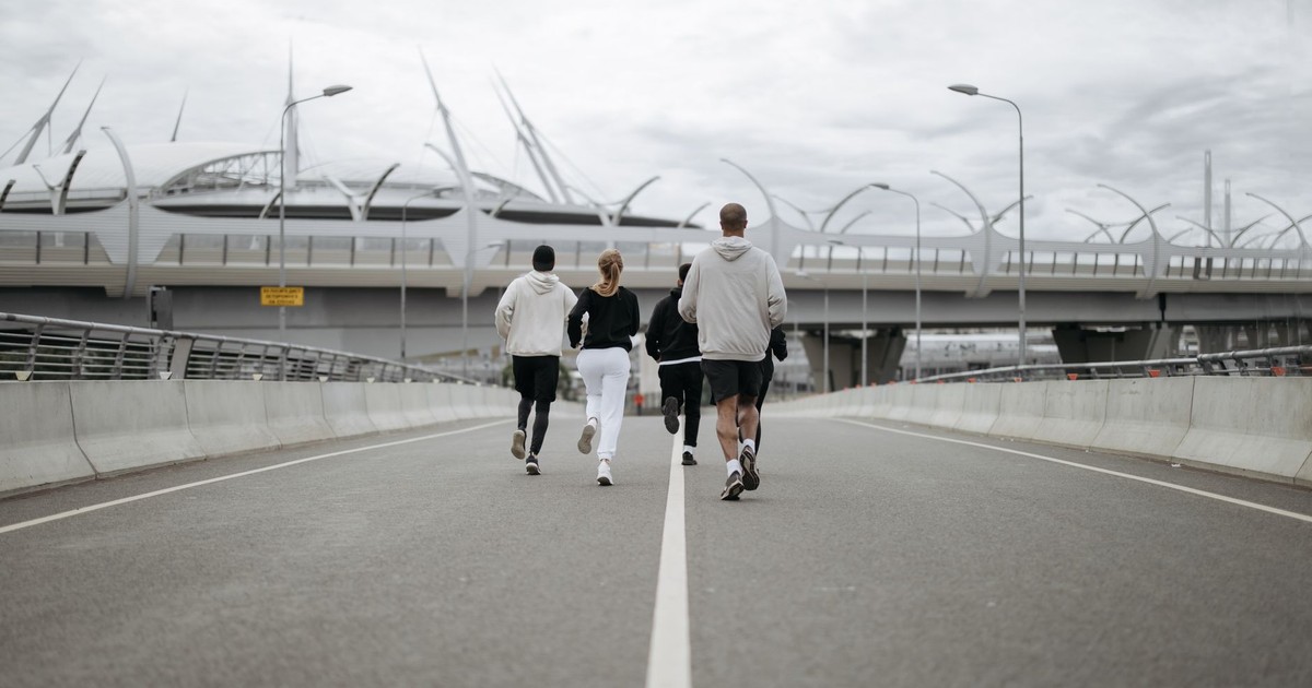 Diverse group jogging on a modern bridge in sportswear, promoting health.