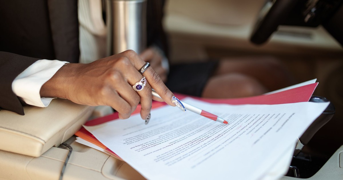 A professional reviewing documents in a car interior, focusing on hand and paperwork.