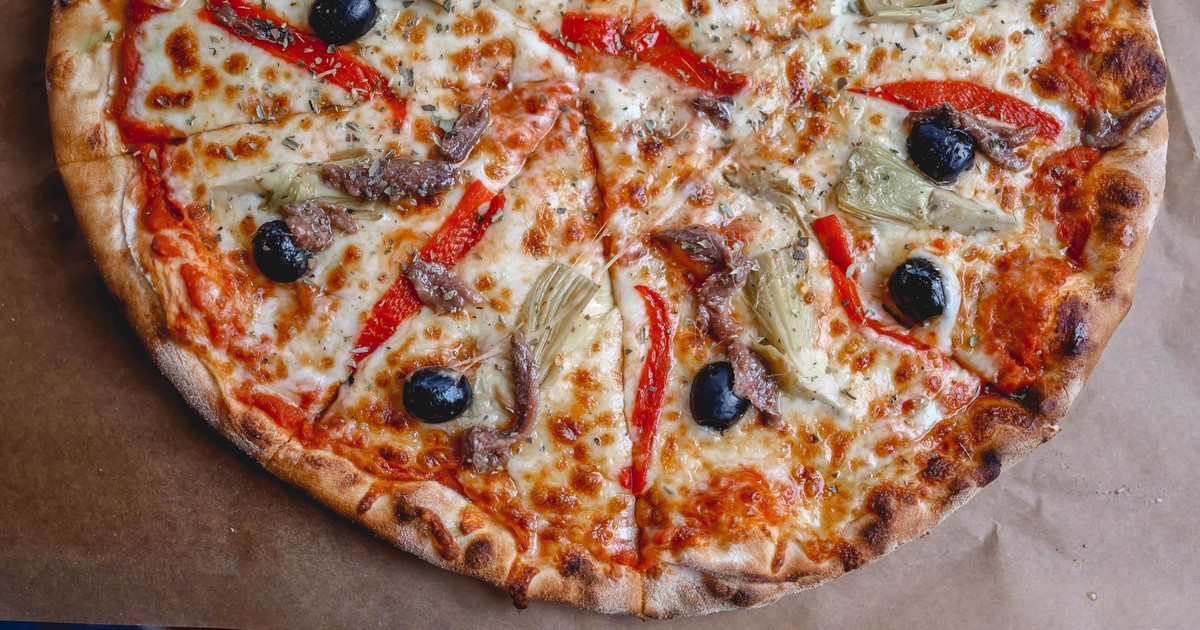 Close-up of a freshly baked pizza topped with black olives, red peppers, and cheese.