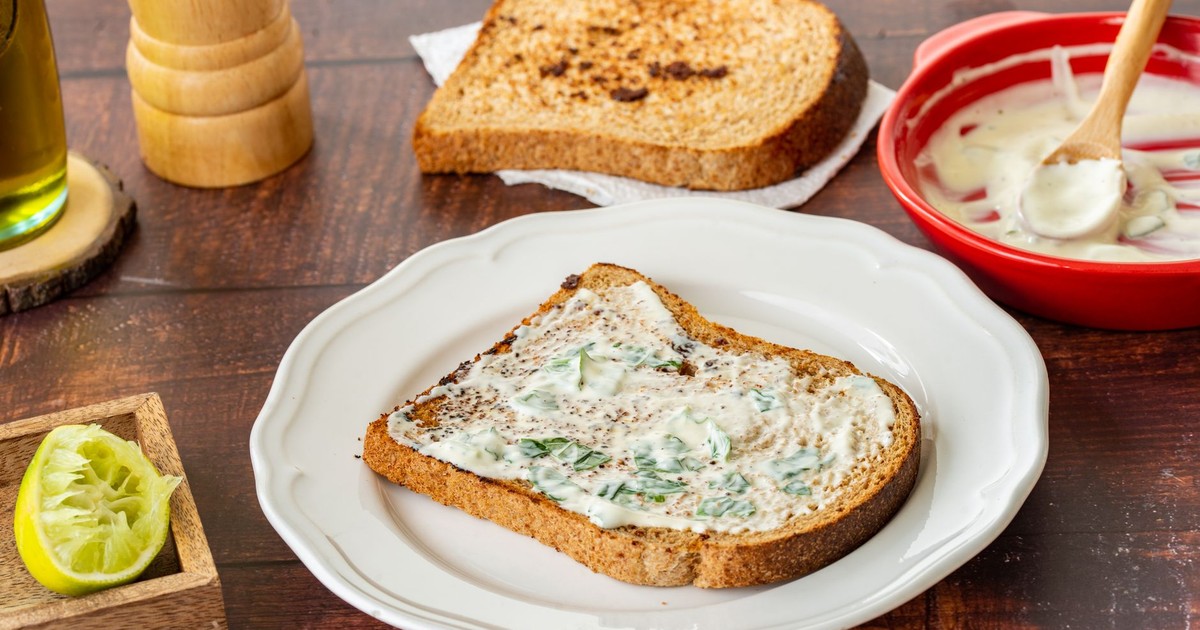 Rustic toast with a creamy herb spread and lemon wedge, perfect for a tasty breakfast.