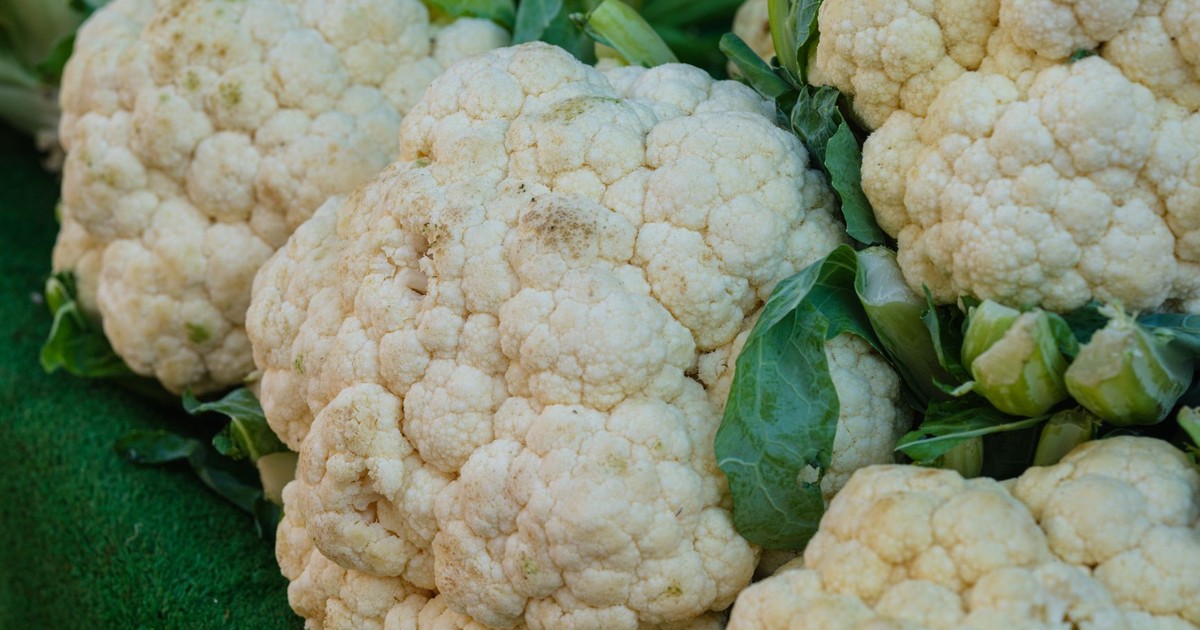 Close-up of fresh cauliflowers with green leaves, showcasing farm freshness and vitality.