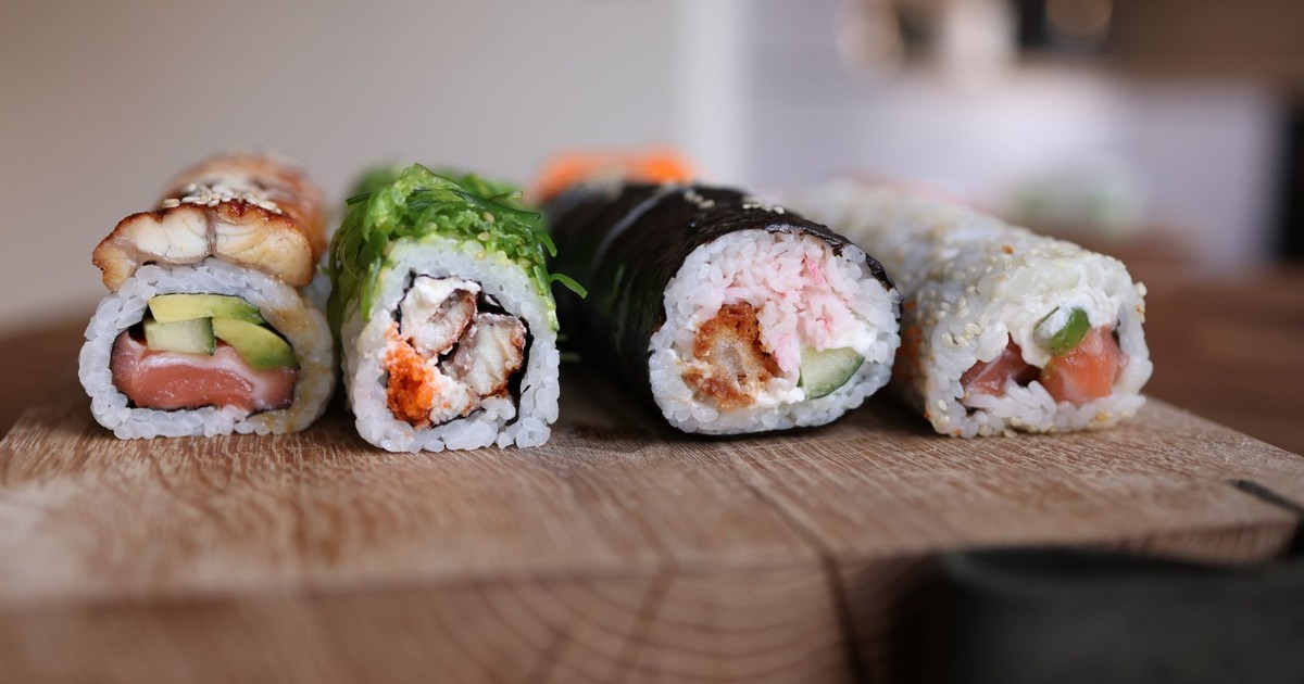 Close-up of assorted sushi rolls on a wooden board showcasing fresh ingredients.