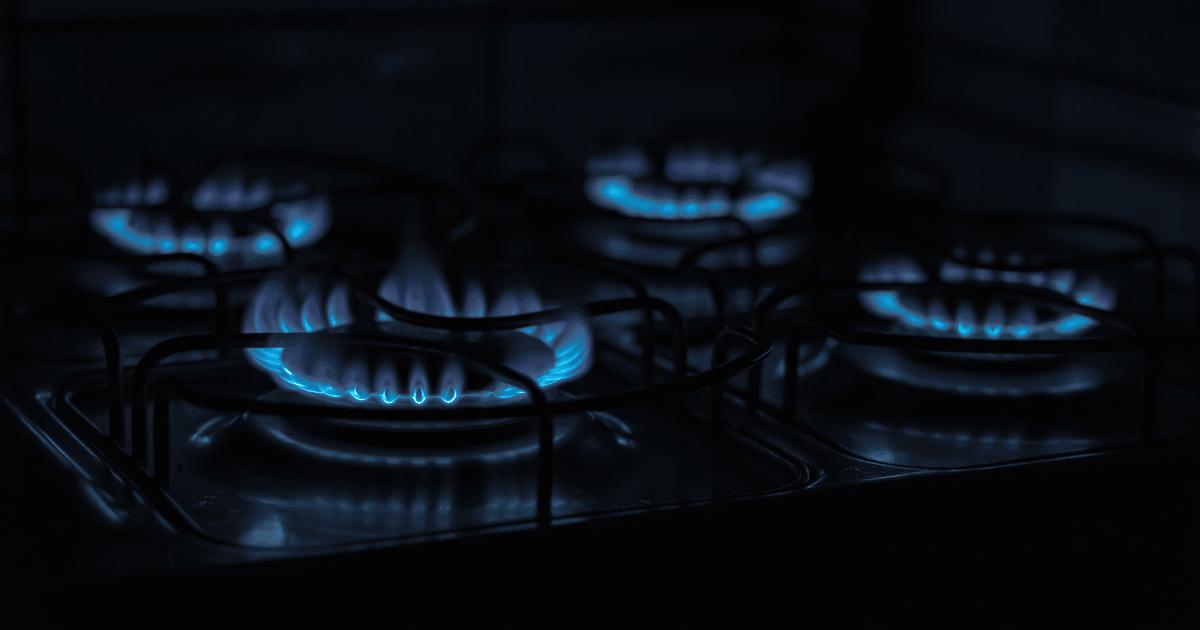 A dark, atmospheric image capturing the blue flames of gas stove burners indoors.