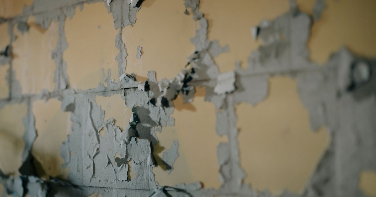 Close-up of aged, peeling paint on a weathered wall showcasing urban decay texture.