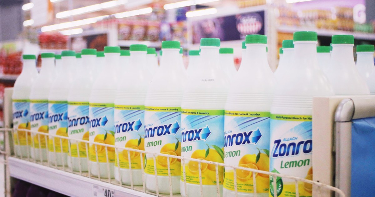 Rows of plastic bottles of bleach with smell of lemon placed on shelves in supermarket