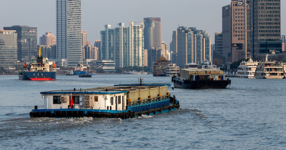 Barges navigate the Huangpu River against the stunning backdrop of Shanghai's modern skyscrapers.