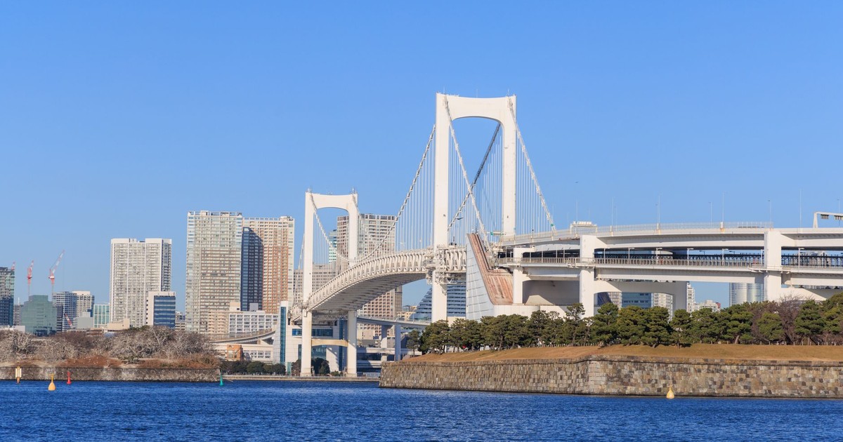 View of the Rainbow Bridge and Tokyo skyline on a bright day, highlighting architectural beauty.