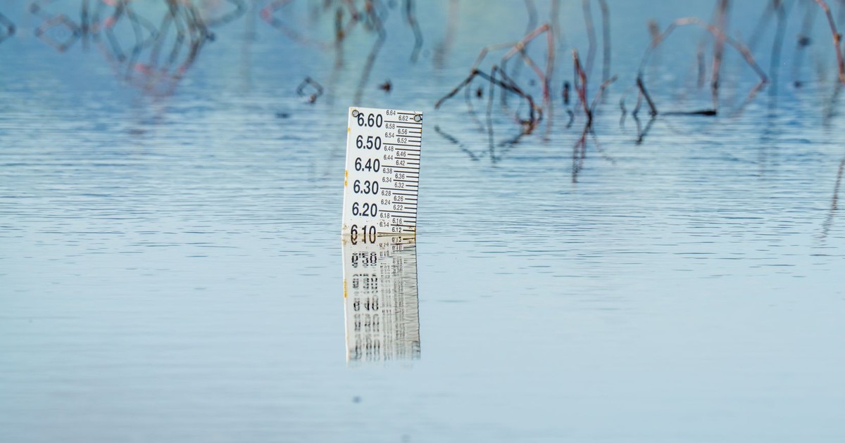 Close-up of a flood gauge in water, reflecting calm surroundings. Perfect for environmental themes.