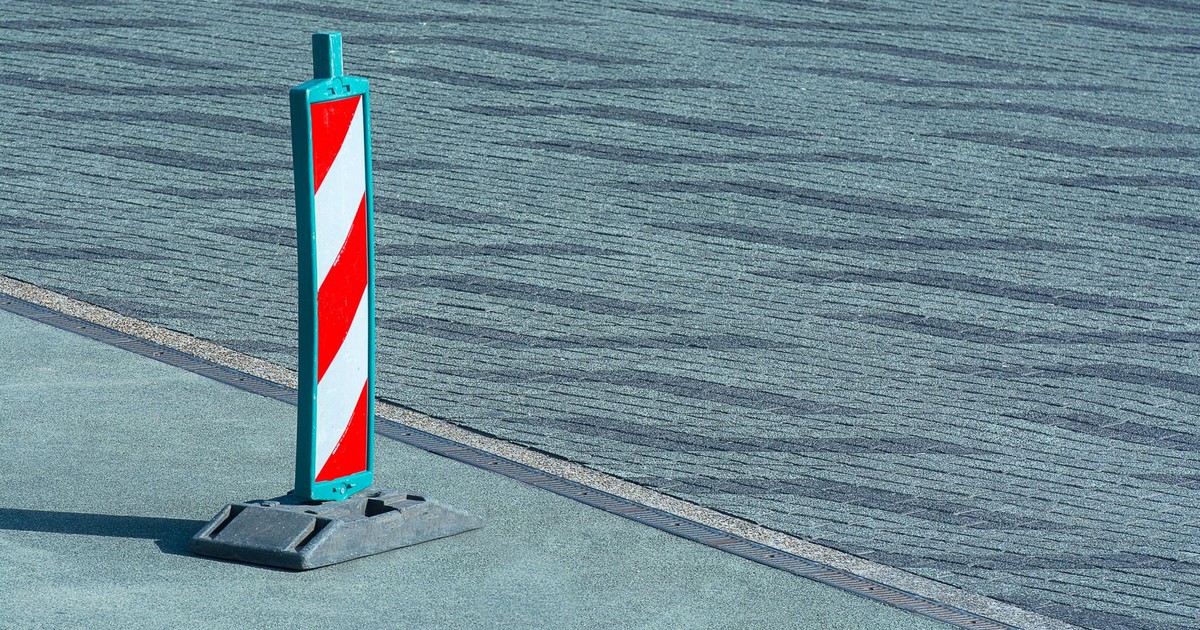 A red and white traffic cone on a textured sidewalk in Rotterdam.