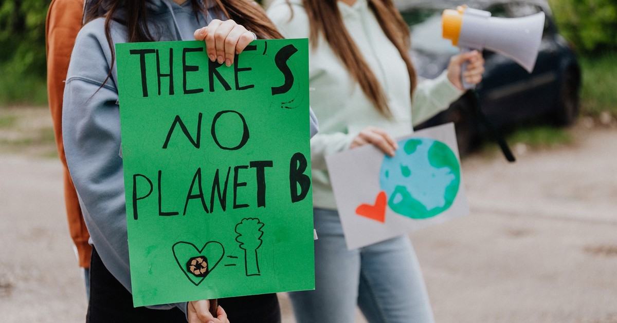 Young adults at a climate change protest holding eco-friendly posters outdoors.