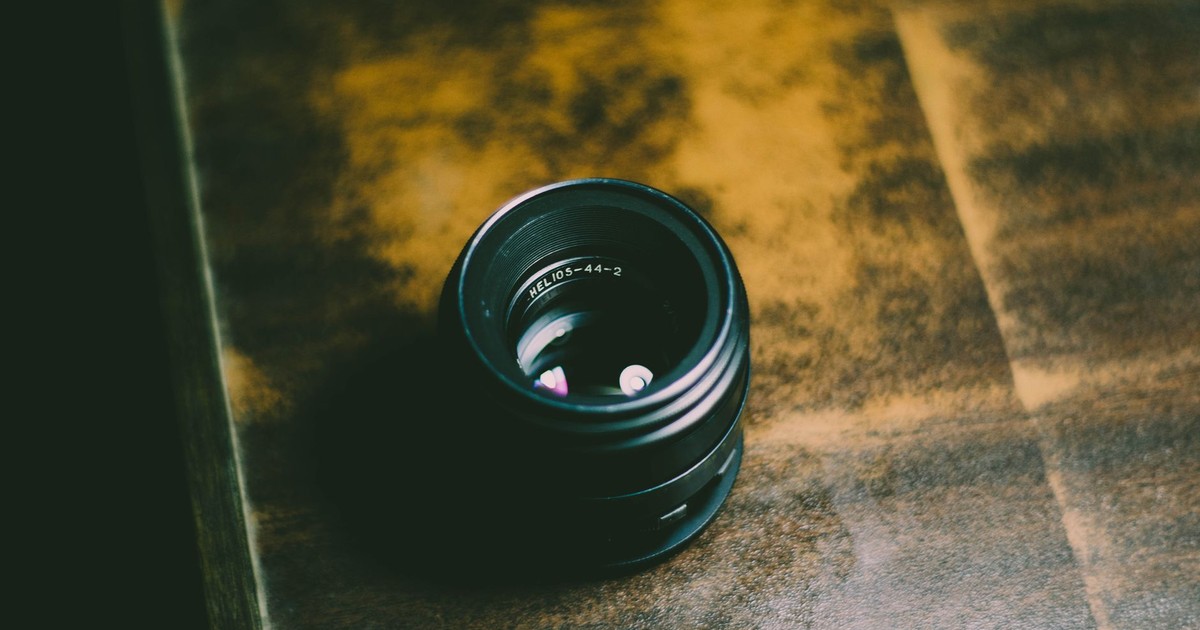 Top-down view of a vintage Helios camera lens placed on a rustic wooden table.