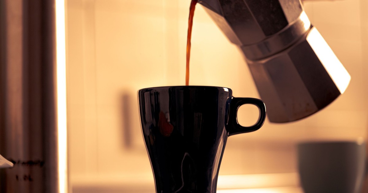 Warm morning coffee being poured into a cup from a classic moka pot.