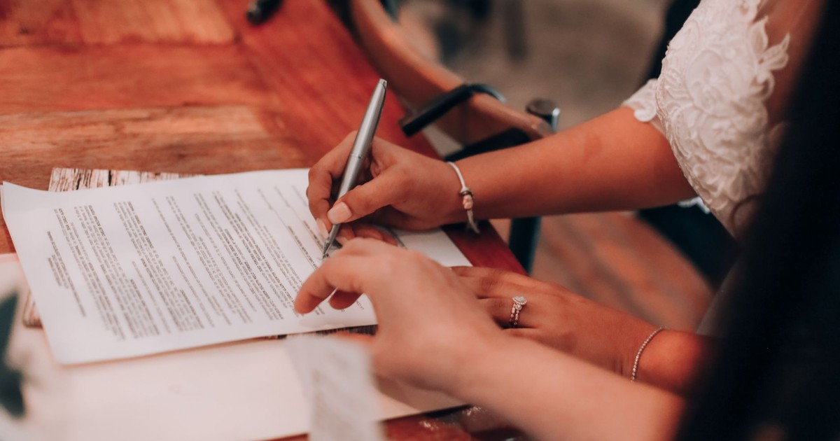 Hands signing an important document at a wooden table, symbolizing agreement and commitment.