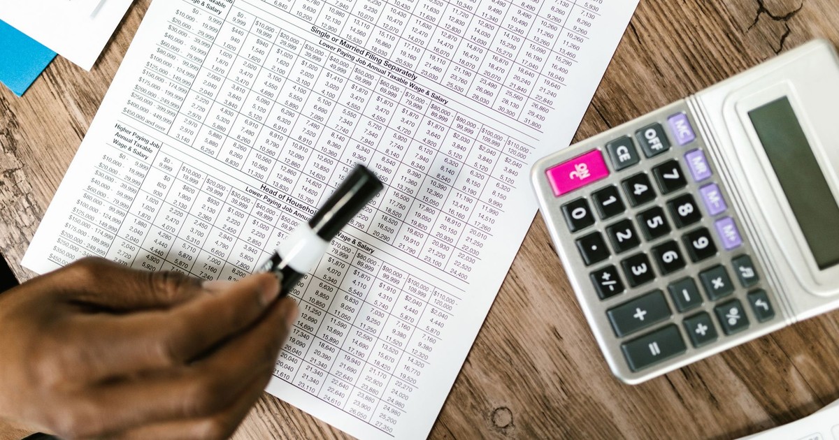 Close-up of tax documents and calculator on wooden table, highlighting financial analysis.