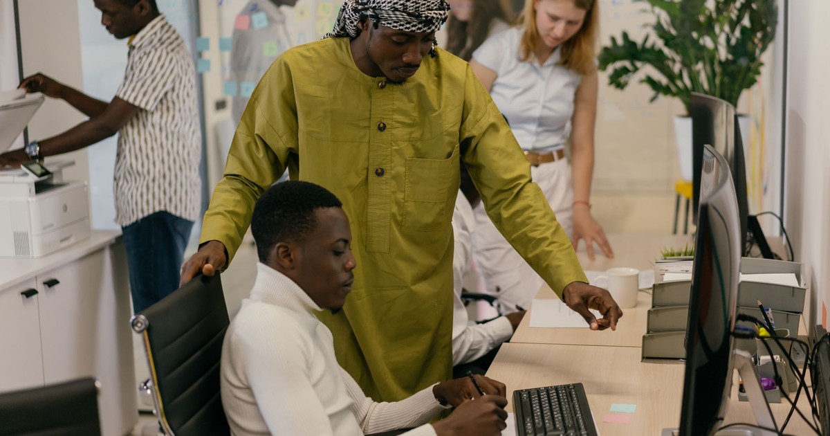Multicultural team working collaboratively in a modern office setting with computers and documents.