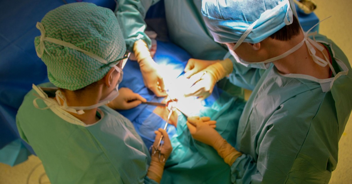 Surgeons in sterile attire performing surgery with precision in a hospital operating room.