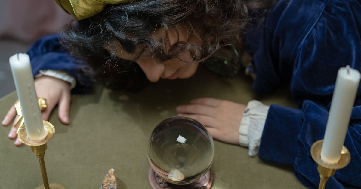 A woman in a fortune teller setting with crystal ball and candles.