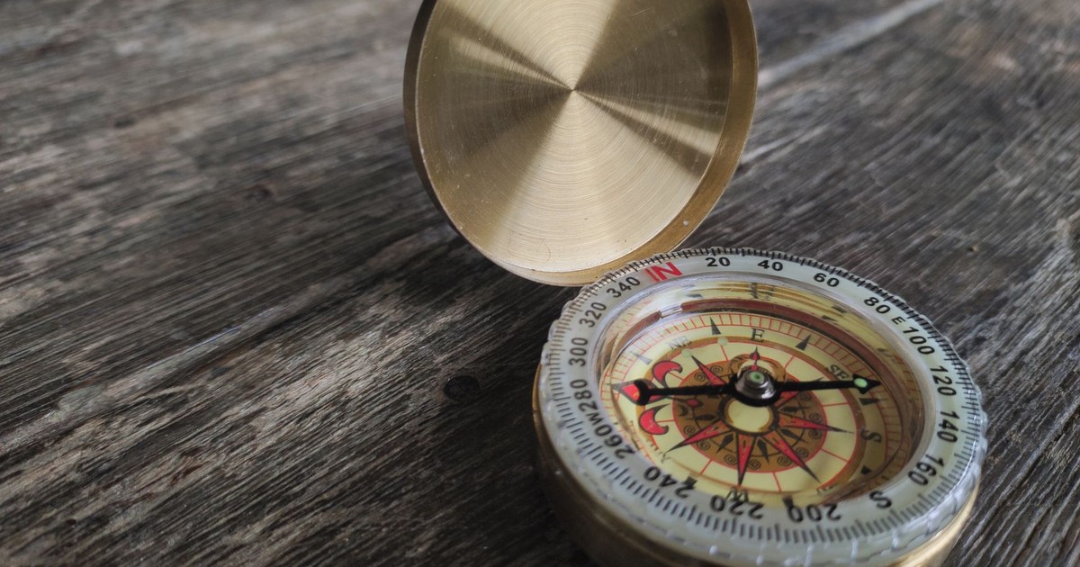 Close-up of a brass compass on a textured wooden surface, symbolizing exploration.