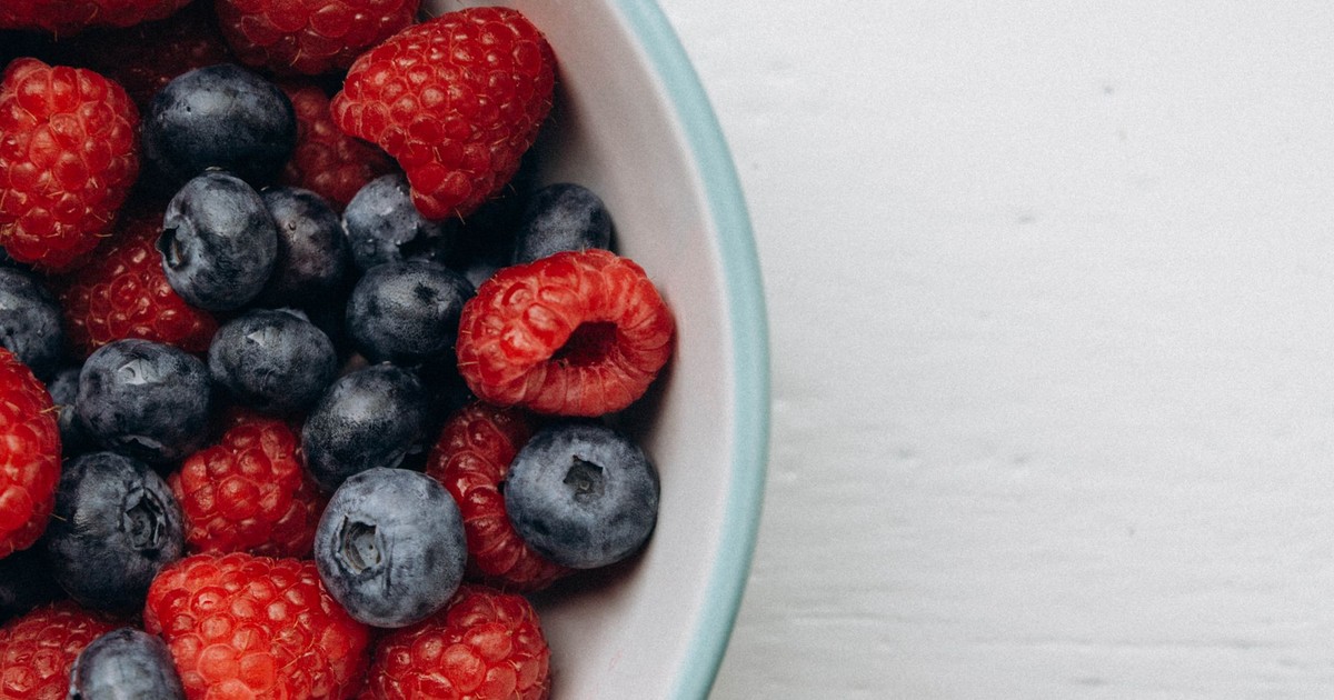 Close-up of fresh raspberries and blueberries in a white bowl, perfect for healthy eating concepts.