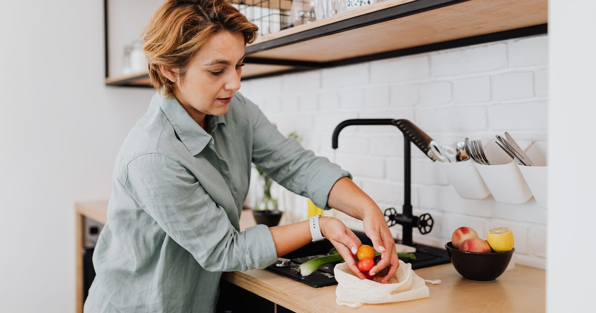 Woman preparing fresh vegetables in a sleek kitchen setting, showcasing culinary activities.