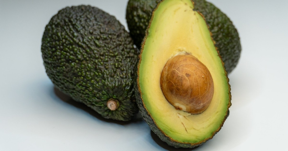 Close-up view of a ripe avocado halved, revealing its seed against a smooth background.