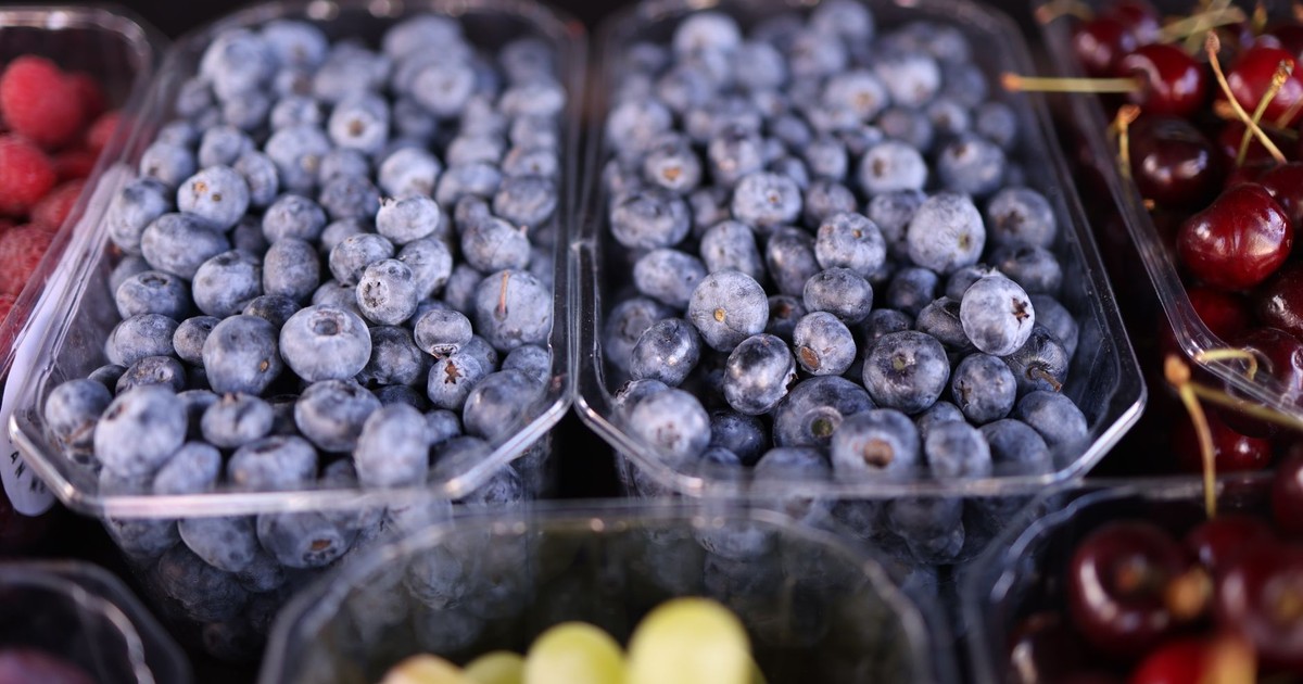 Colorful display of fresh blueberries, raspberries, and grapes at a market. Perfect for healthy eating themes.