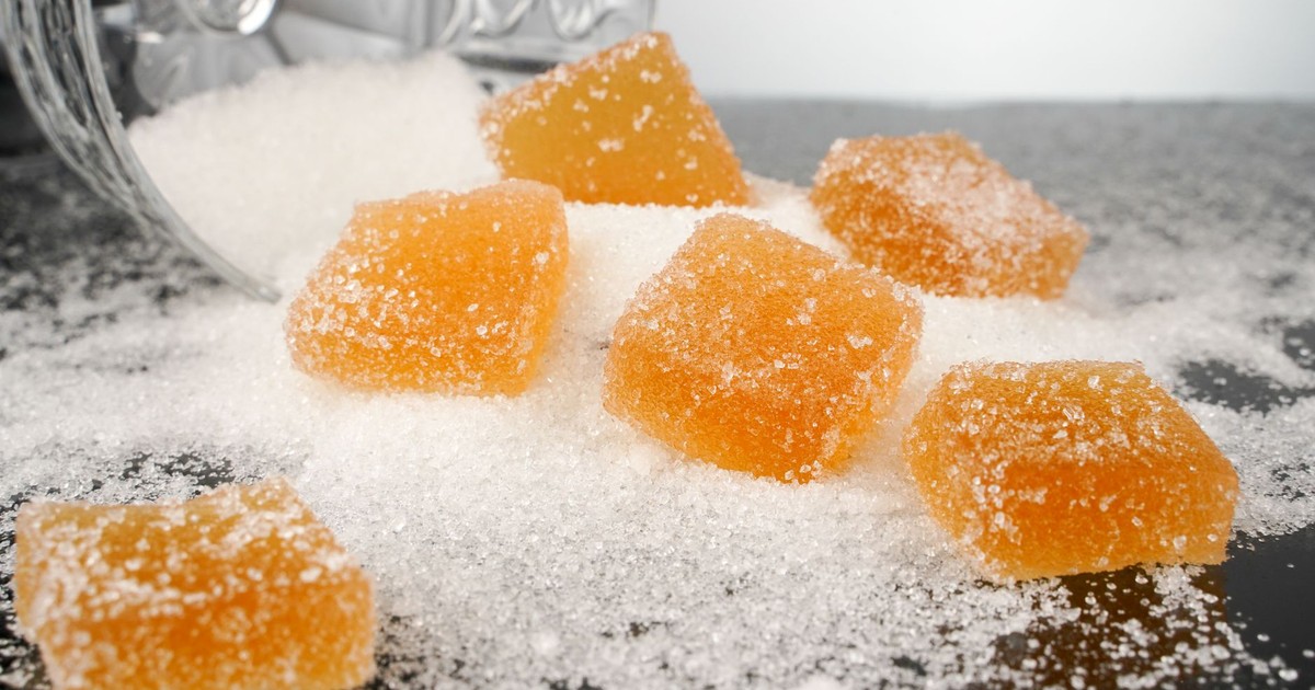 Close-up view of sugar-coated orange gummy candies spilled on a surface.