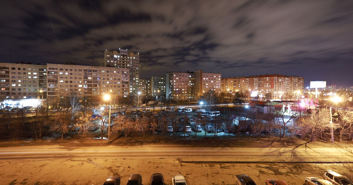 A vibrant cityscape of Chelyabinsk at night showcasing illuminated apartments and streetlights.