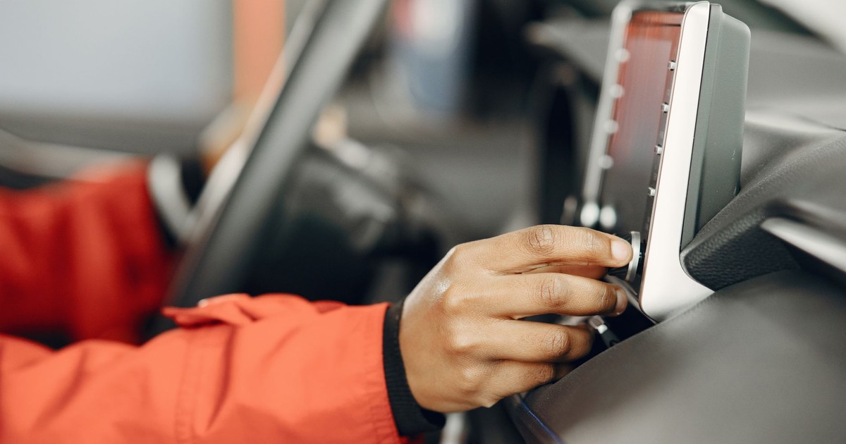 Close-up of a hand adjusting the car stereo while driving, highlighting technology and focus.