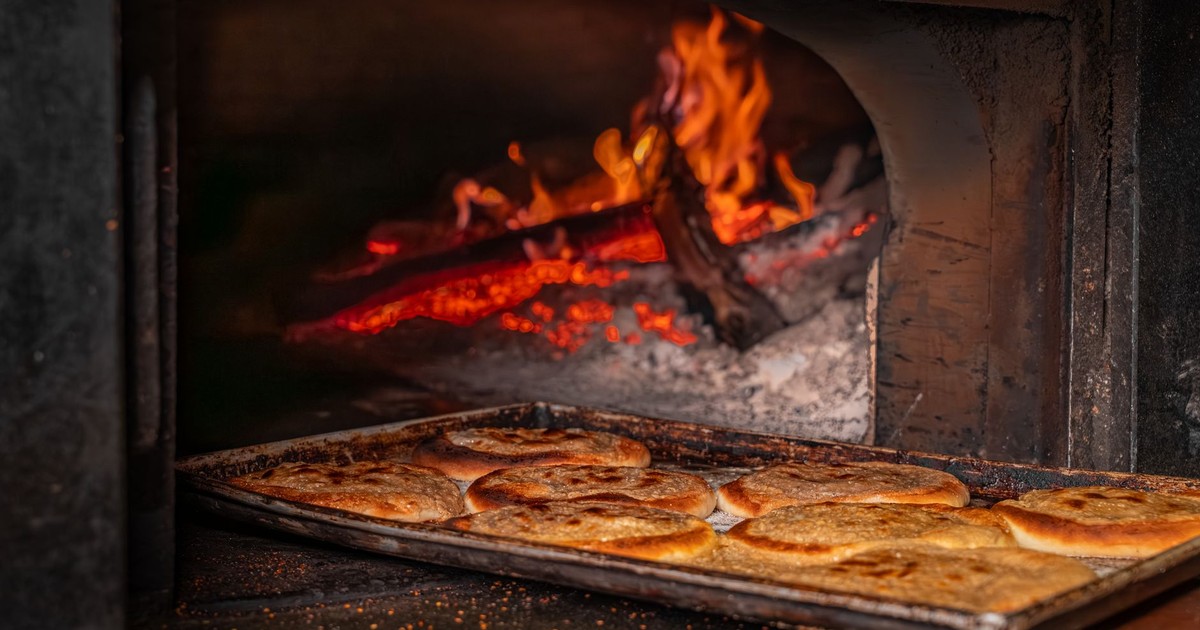 Rustic bread baking in a traditional wood-fired oven, showcasing the rich texture and flame-cooked method.