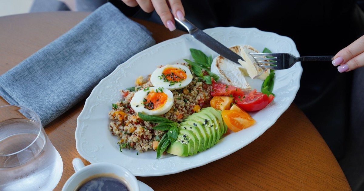 A delicious and healthy breakfast featuring avocado, eggs, and coffee served on a wooden table.