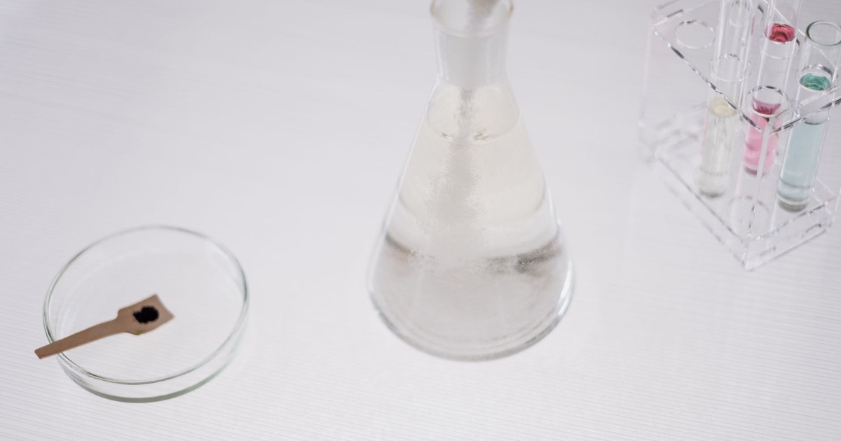 Close-up of laboratory glassware including a flask, test tubes, and petri dish on a white surface.