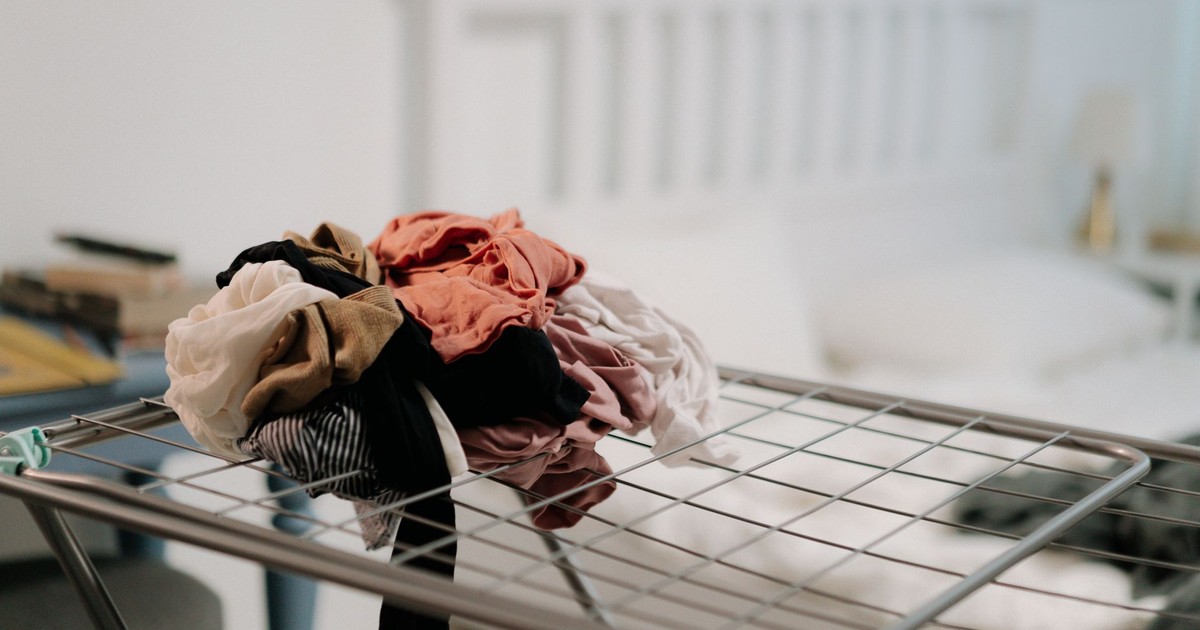 Pile of clothes on a drying rack in a cozy bedroom setting with natural light.
