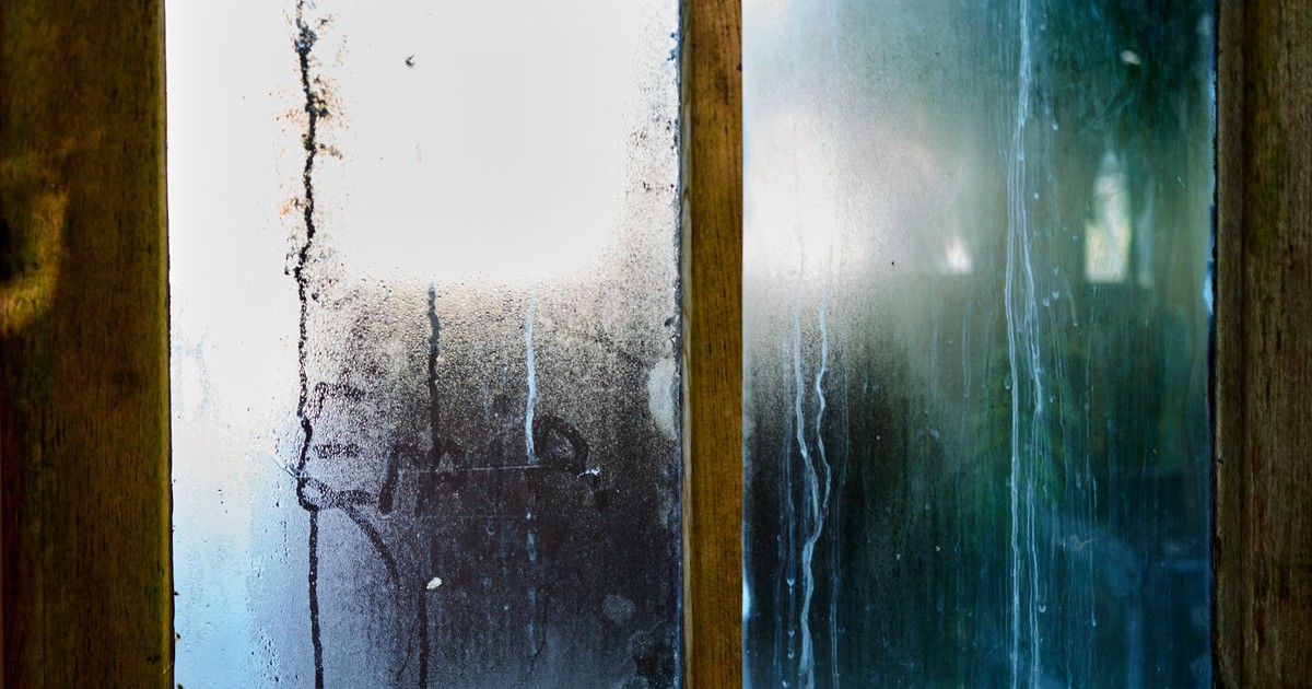 Close-up of a moist wooden window pane with condensation creating artistic streaks in Leiden, Netherlands.
