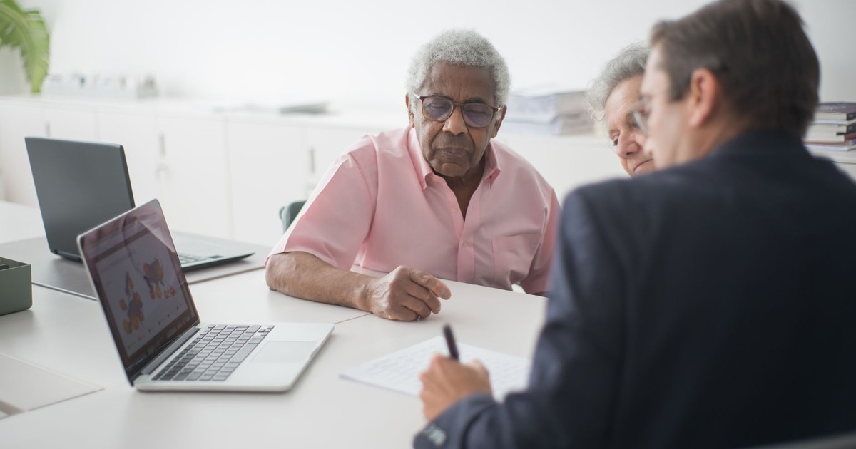 Senior couple discussing insurance options with a consultant in an office setting.