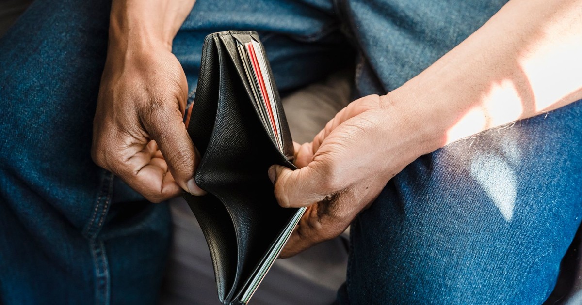 Close-up of a man holding an empty wallet, symbolizing financial crisis and hardship.