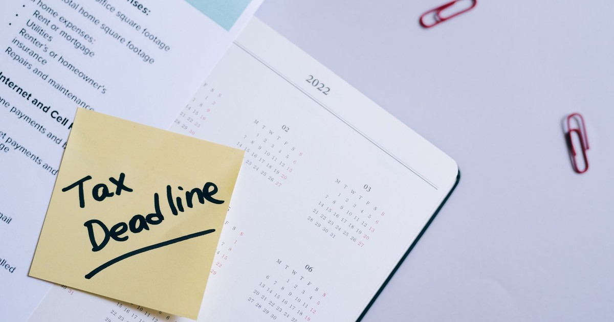 A sticky note highlights tax deadline on a calendar alongside documents, emphasizing financial planning.