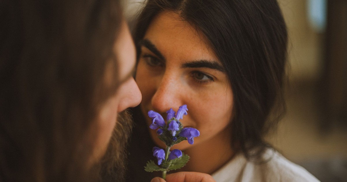 A couple sharing an intimate moment with a flower, conveying romance and affection.