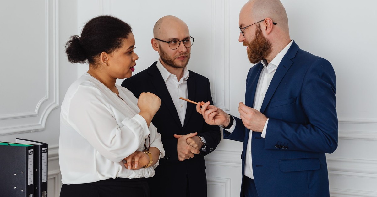 Three professionals engaged in a business discussion in an office setting.