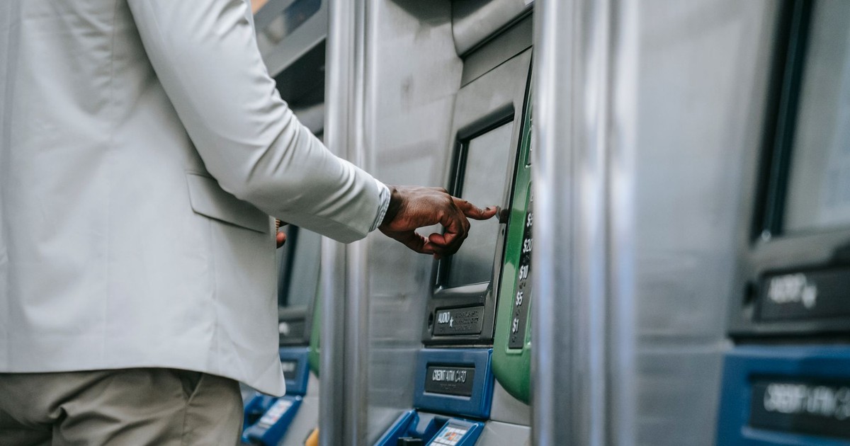 Side view of an adult using a self-service ticket machine indoors.