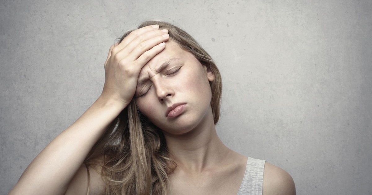 A woman in distress holding her head, expressing emotion and fatigue.