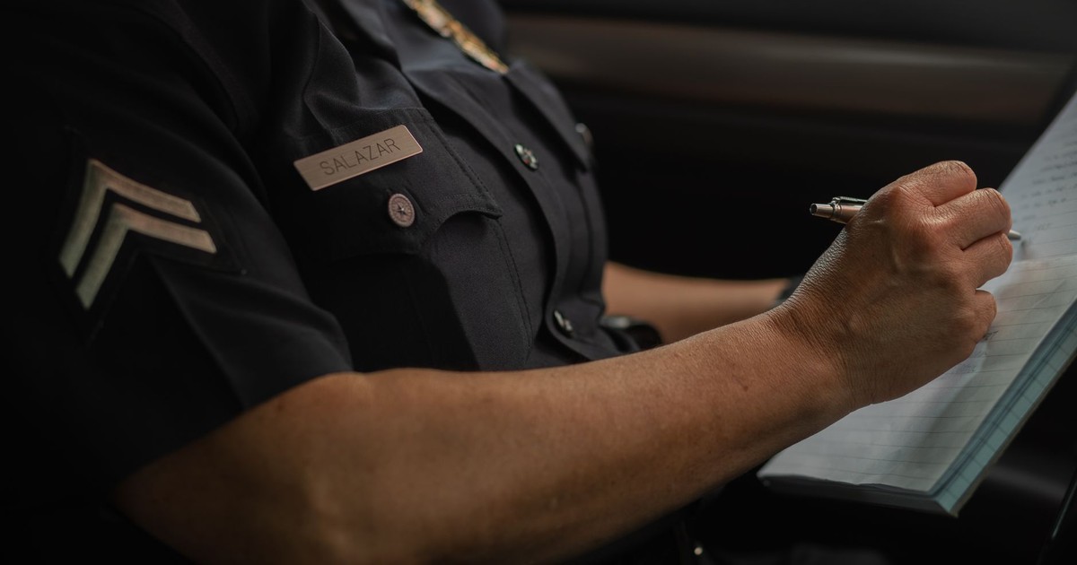 Close-up of a police officer writing in a notebook while sitting in a car, focused detail.