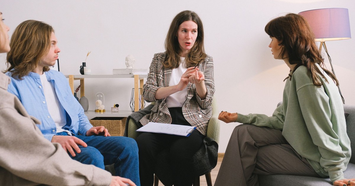 Female therapist during group session talking to female patients gathering in light cozy office