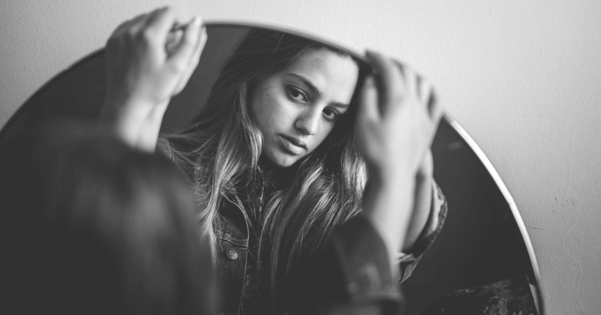 Elegant black and white portrait of a woman reflecting in a mirror.