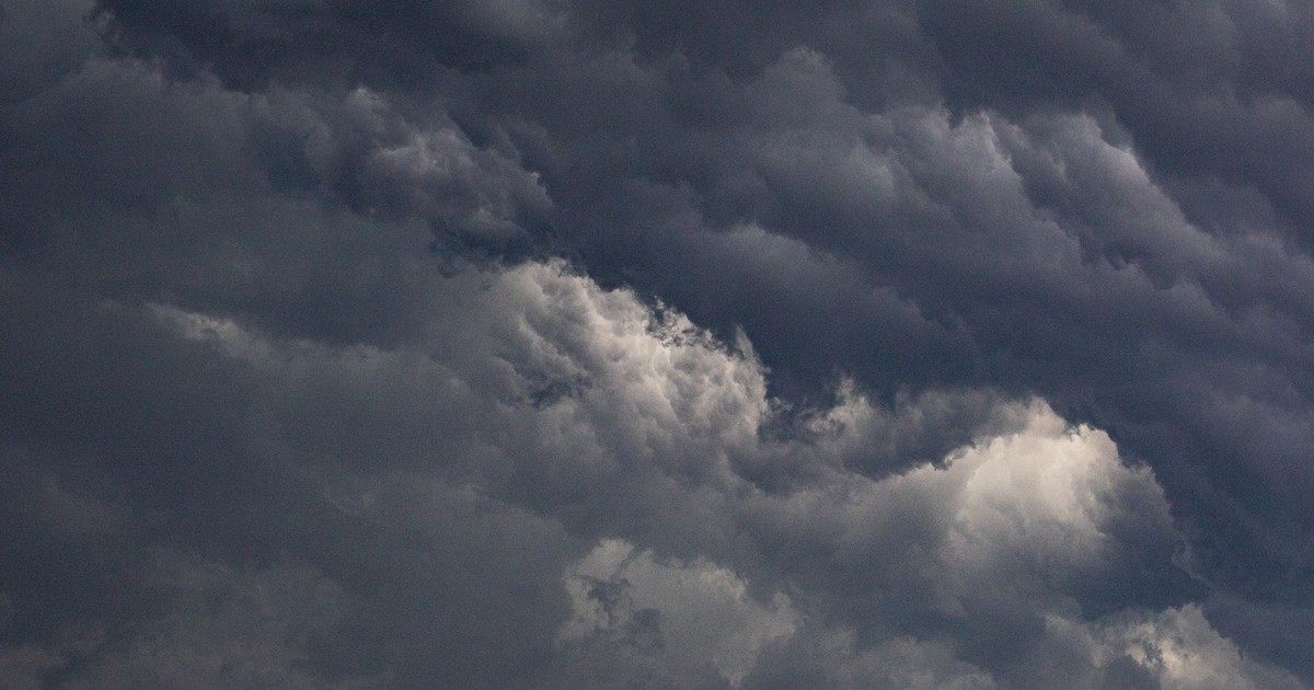 Dark storm clouds loom over city buildings creating a dramatic urban landscape.